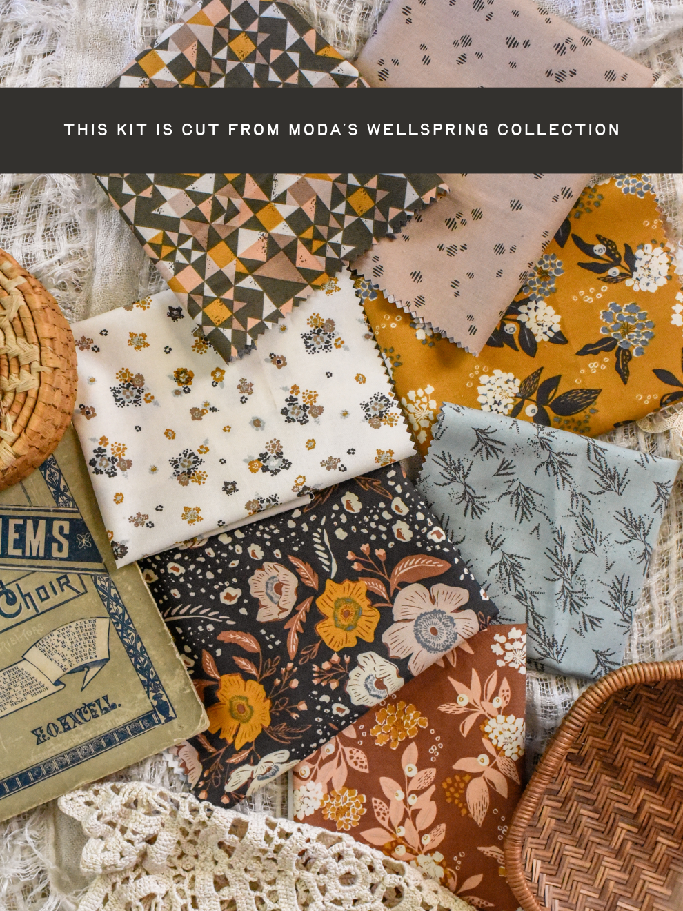 A flat lay of multiple fabric swatches from Moda's Wellspring Collection, showcasing various patterns including floral, geometric, and botanical prints in earthy tones of mustard yellow, dusty pink, cream, and slate blue. The fabrics are styled on a textured white lace background with decorative baskets and a vintage book.