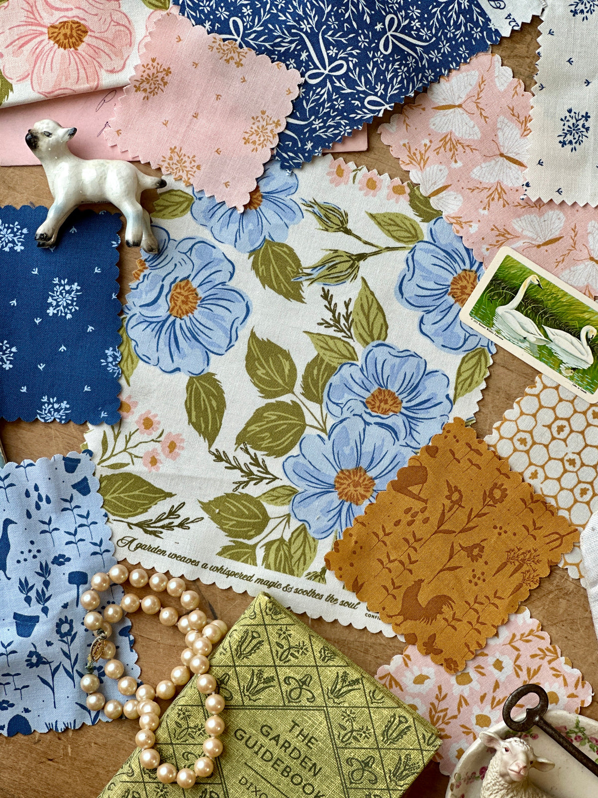 Collection of floral and patterned fabric swatches with decorative items on a wooden surface.