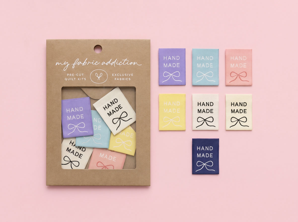 A craft kit package labeled 'my fabric addiction' next to several small fabric swatches in pastel colors, all arranged on a soft pink background.
